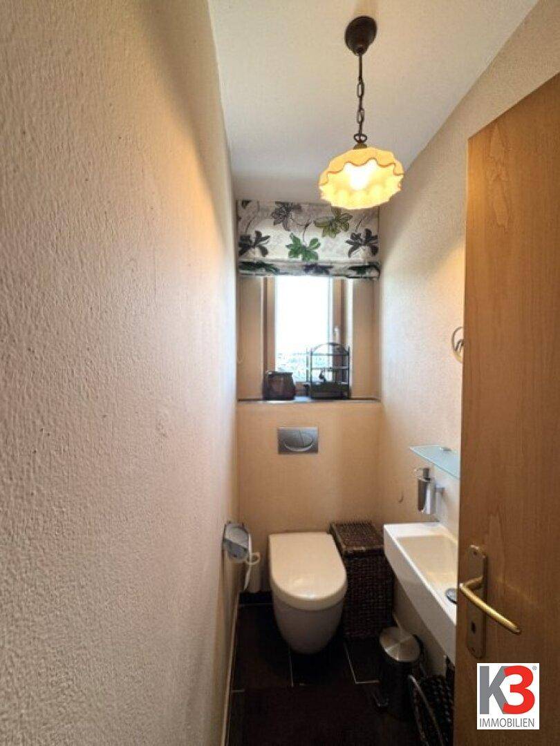 Kleines Gäste-WC mit Fenster, wandhängendem WC und kleinem Waschbecken.