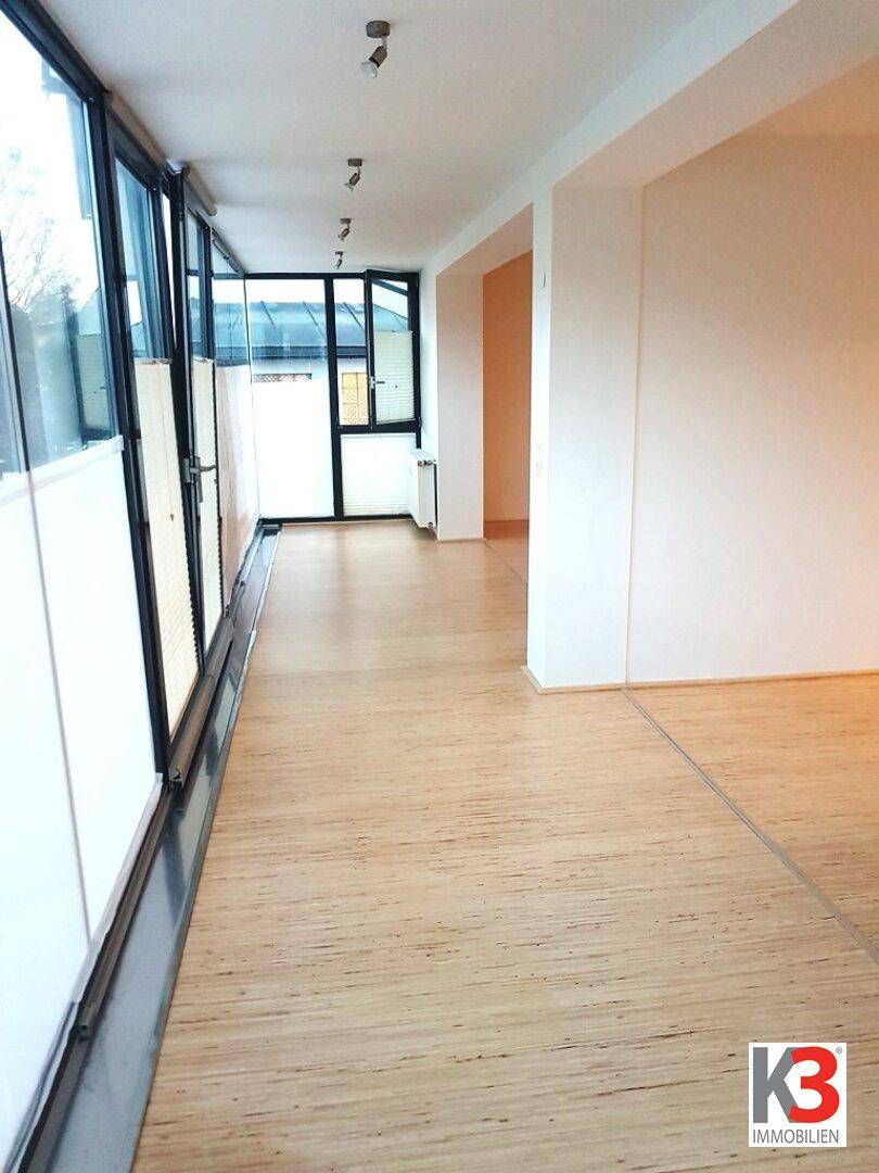 Langer Flur mit Holzboden und einer Fensterfront, die den Raum mit natürlichem Licht erhellt.