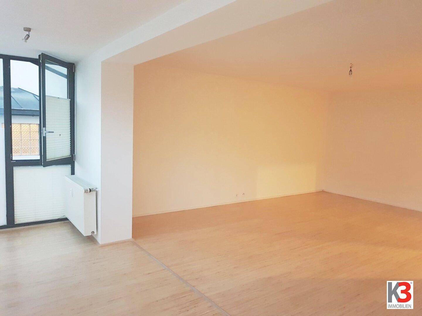 Geräumiger Wohnbereich mit Holzboden, hellen Wänden und einem geöffneten Fenster für frische Luft.