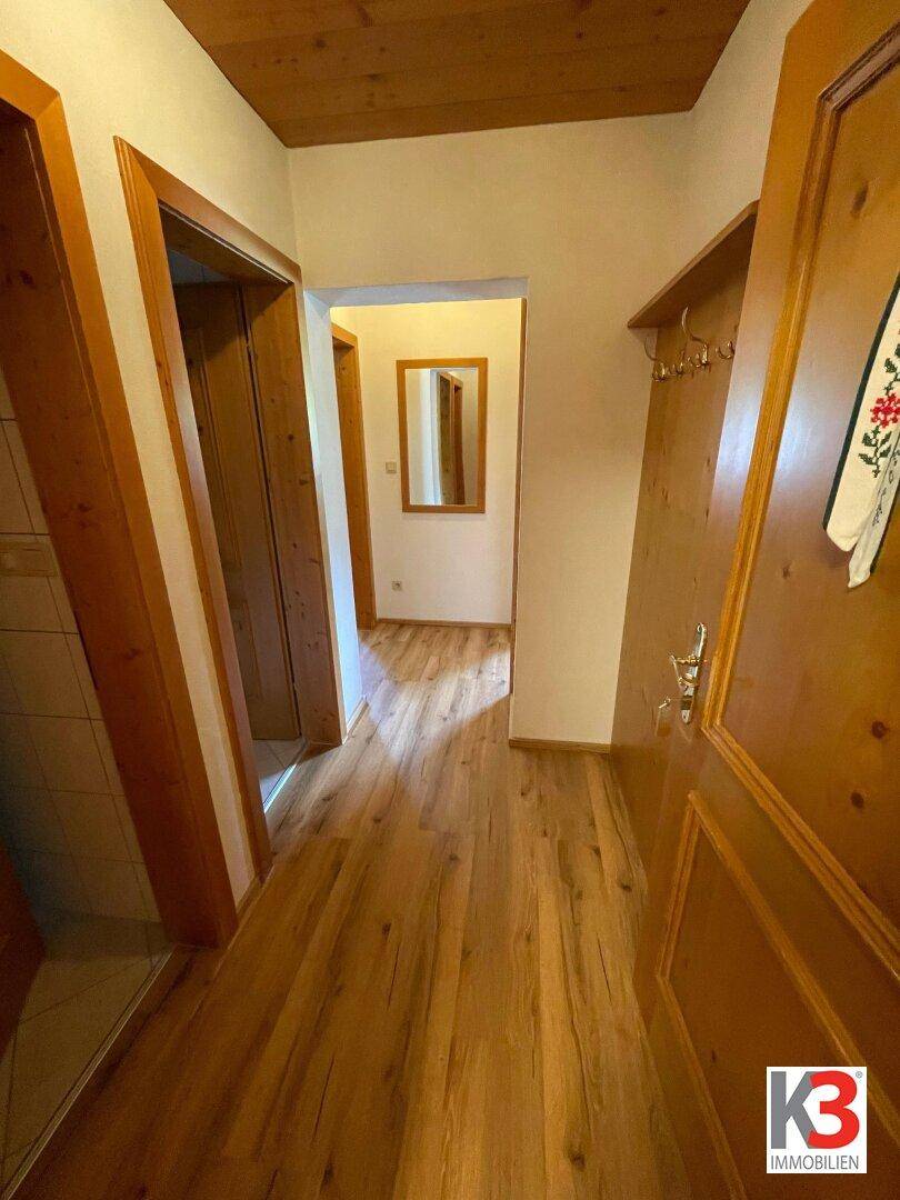 Flur mit Holzboden und Holzrahmen, der zu weiteren Räumen führt.