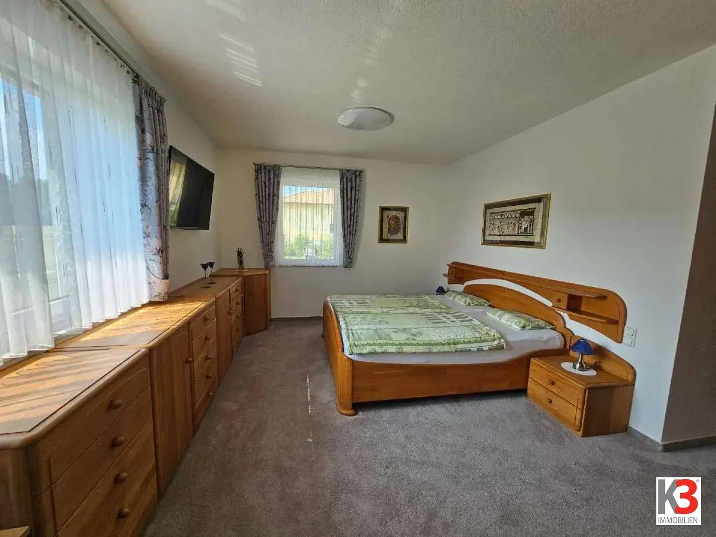 Schlafzimmer mit Holzdoppelbett, maßgefertigten Holzschränken und Fenster.