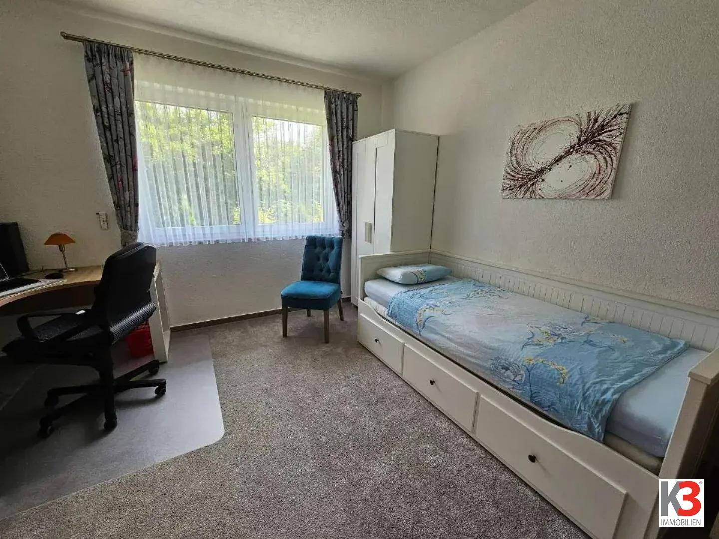 Kinder- oder Gästezimmer mit Einzelbett, Schreibtisch und großem Fenster.