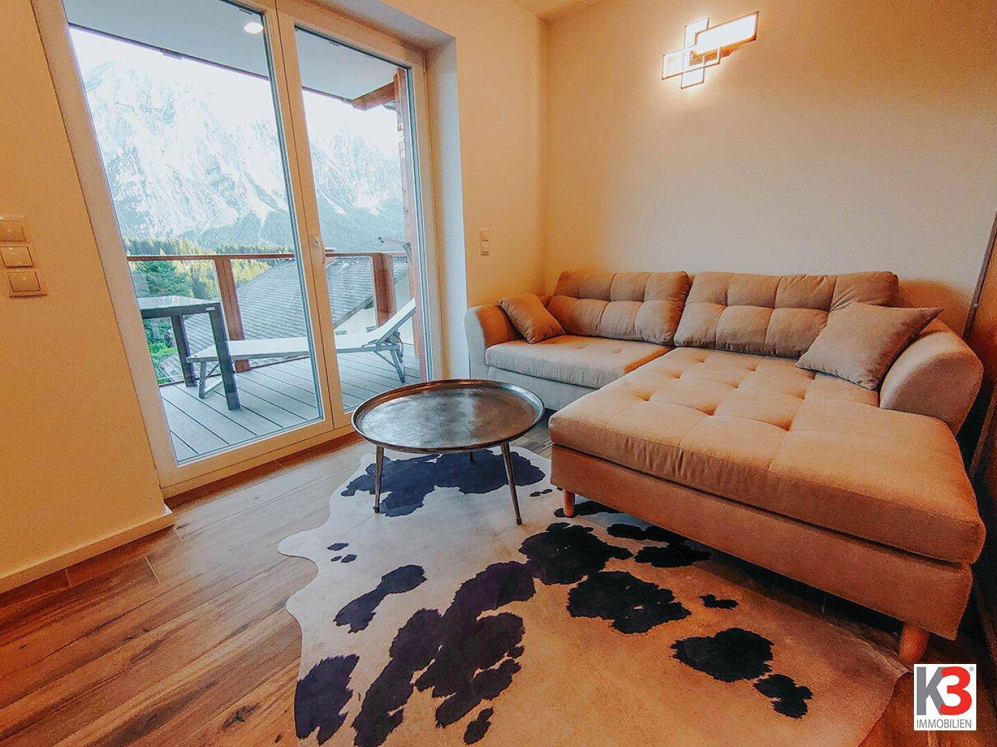 Gemütlicher Wohnbereich mit großem Sofa und beeindruckendem Bergblick vom Balkon.