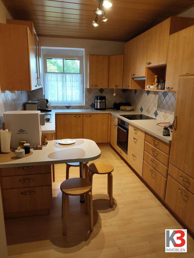 Funktionale Küche mit Holzschränken, Essbereich und einem Fenster für natürliches Licht.