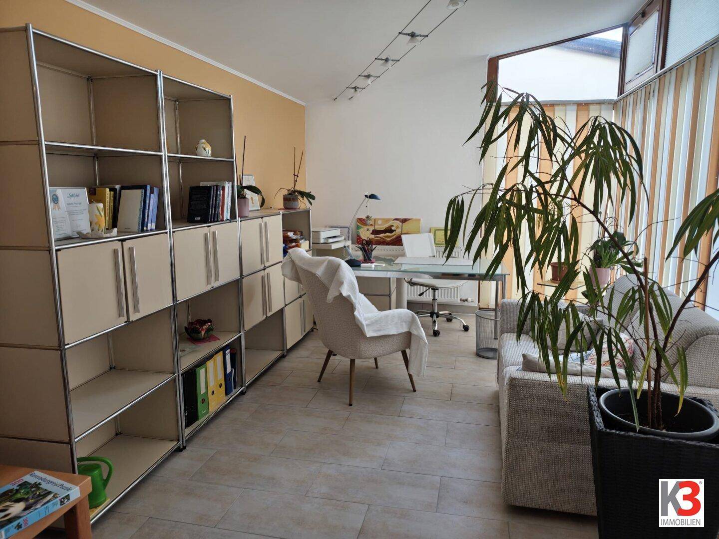 Geräumiger Wintergarten mit Regalsystem, der als Büro und zusätzlicher Wohnraum genutzt wird.