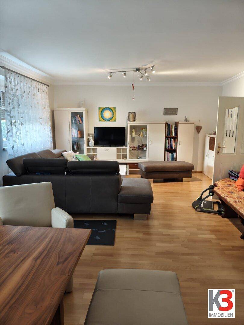 Gemütliches Wohnzimmer mit Laminatboden, großem Sofa und einem Unterhaltungssystem.