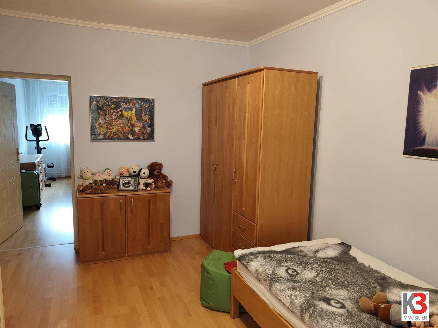 Helles Kinderzimmer mit Laminatboden, Schrank und Spielzeug, bietet eine freundliche Atmosphäre.