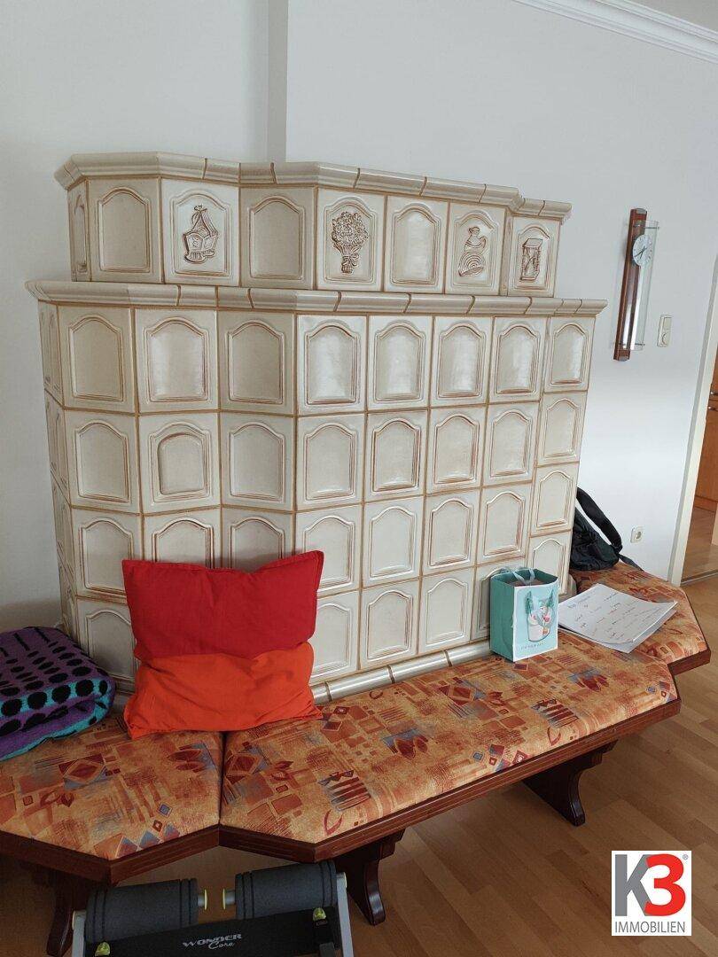 Traditioneller Kachelofen mit Sitzbank, der Wärme und Gemütlichkeit in den Wohnbereich bringt.