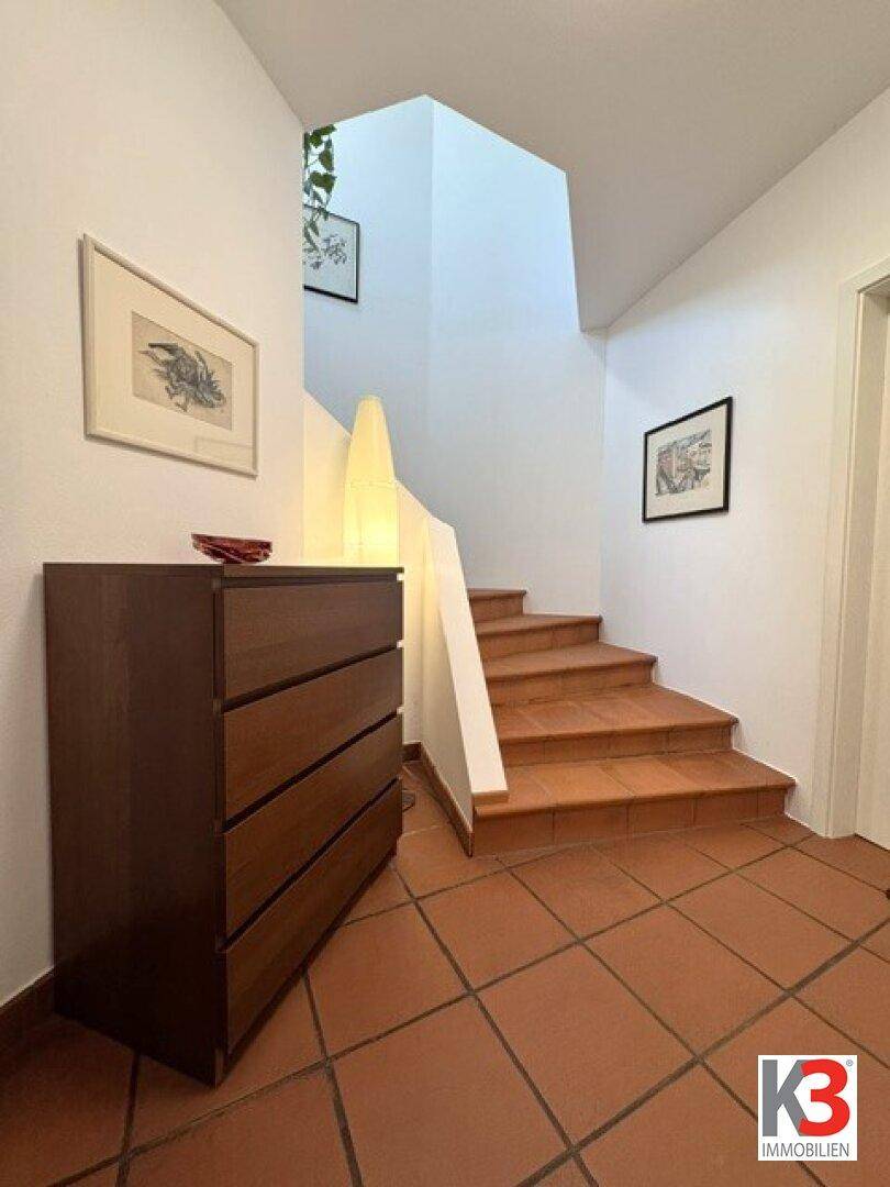 Heller Flur mit Terrakotta-Fliesenboden und Treppe, die in die oberen Stockwerke führt.