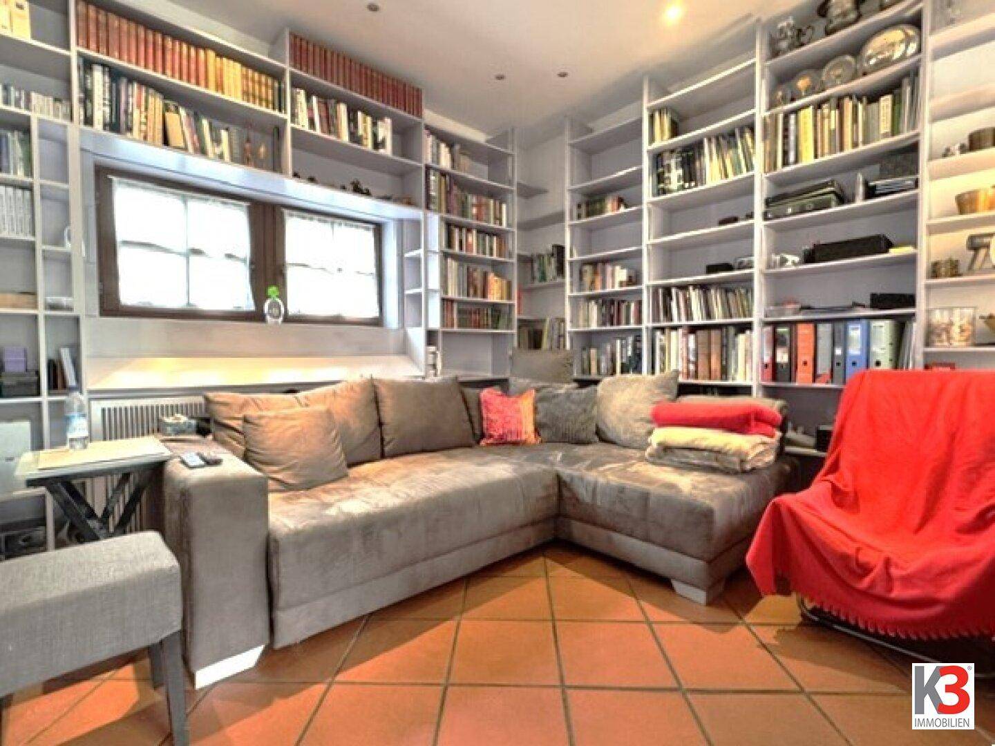 Wohnzimmer mit großem Ecksofa und raumhohen Bücherregalen, ideal für entspannte Stunden.