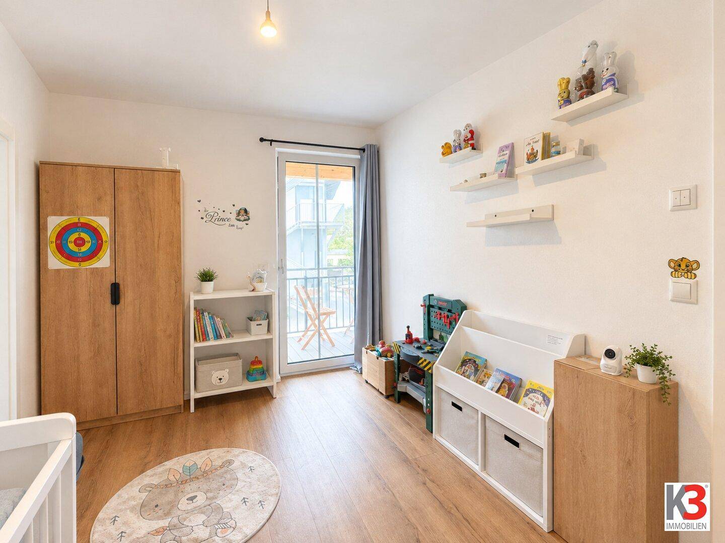 Kinderzimmer mit Holzboden, Schrank und Zugang zu einem französischen Balkon.