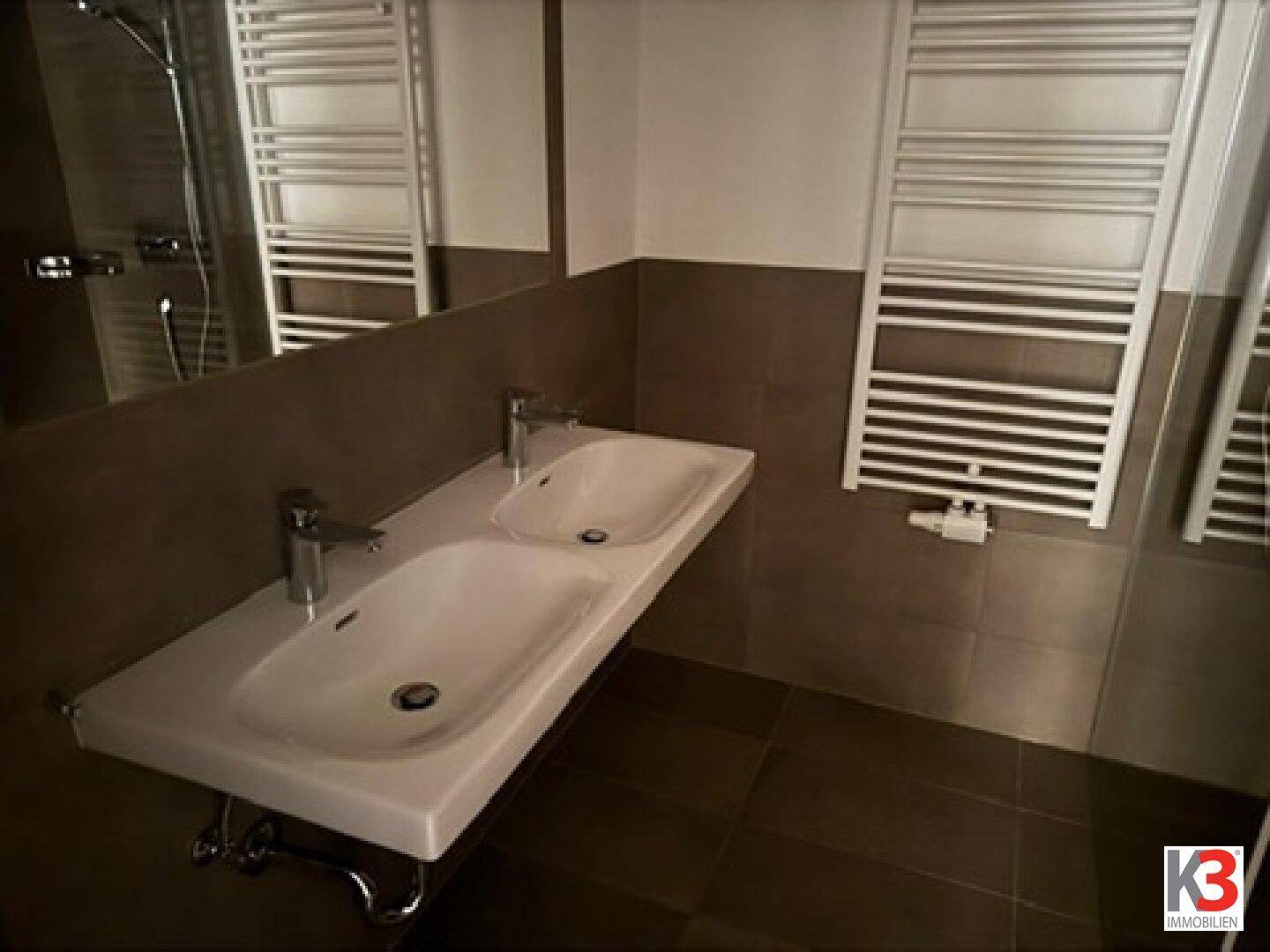 Modernes Badezimmer mit Doppelwaschbecken, großem Spiegel und Handtuchheizkörpern.