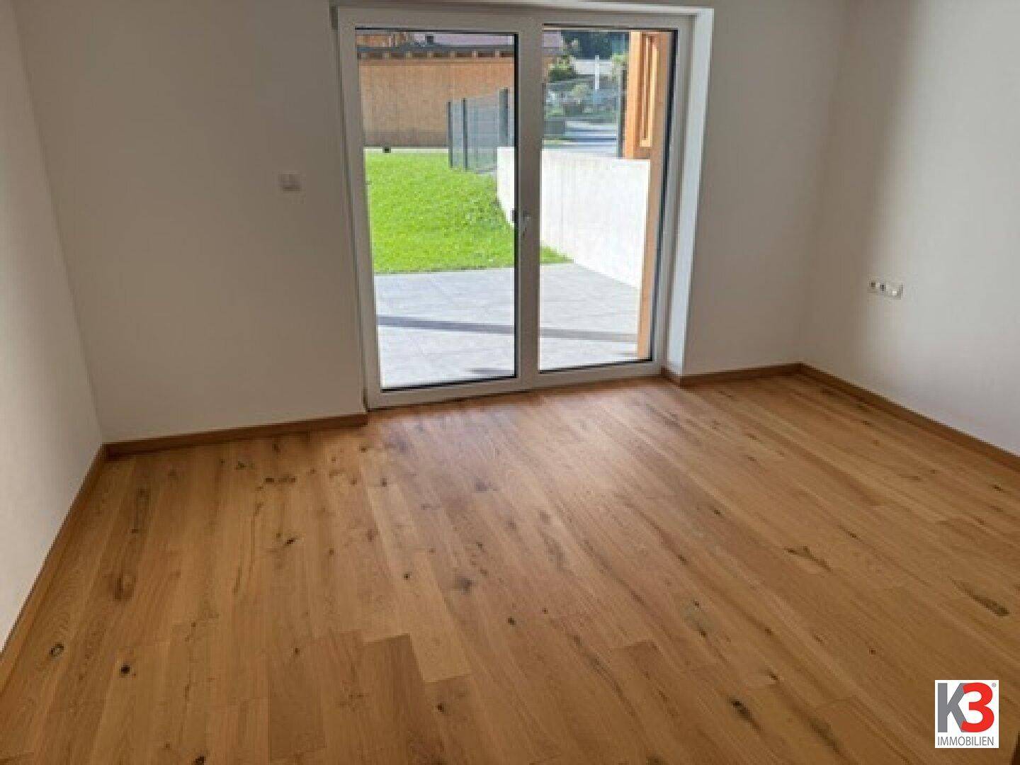 Helles Zimmer mit Holzboden und direktem Zugang zur Terrasse und Garten.