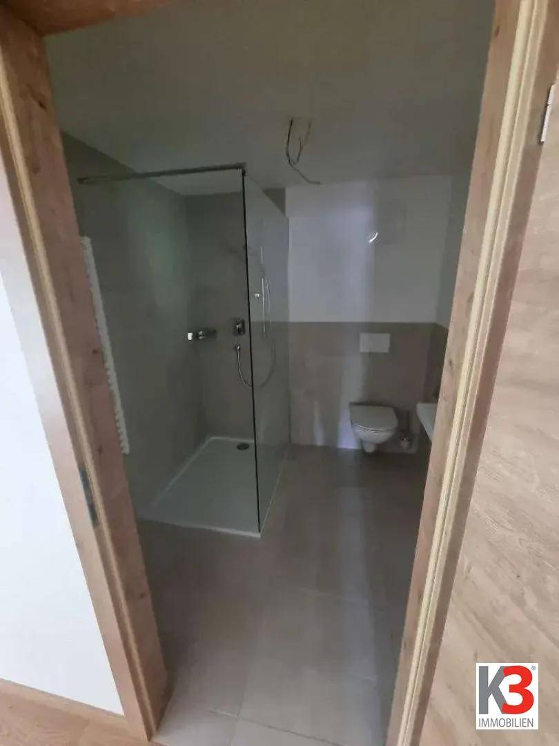 Modernes Badezimmer mit ebenerdiger Dusche, Wand-WC und Fliesenboden.