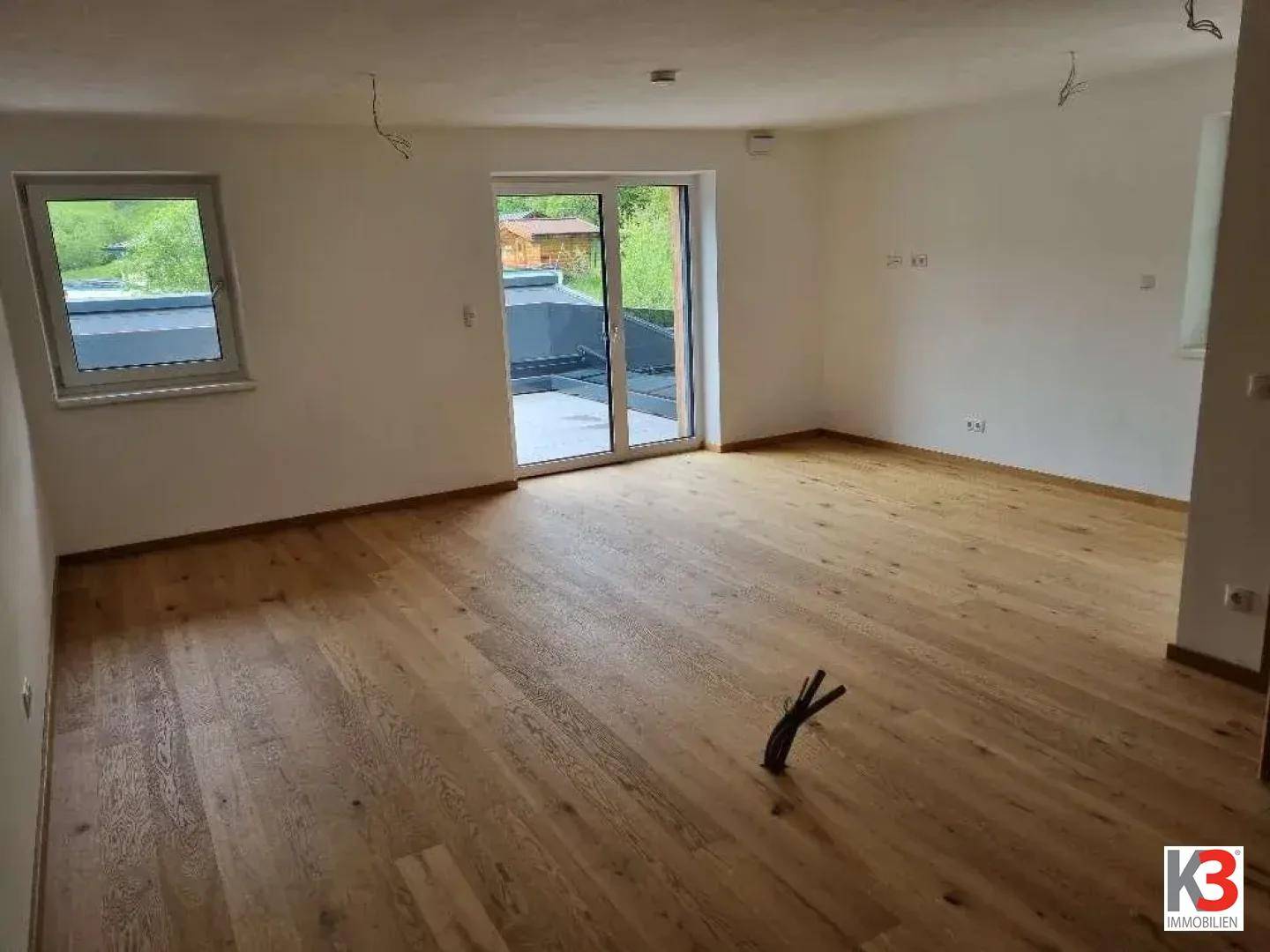 Helles Wohnzimmer mit Holzboden und großer Schiebetür, die zu einer Terrasse führt.