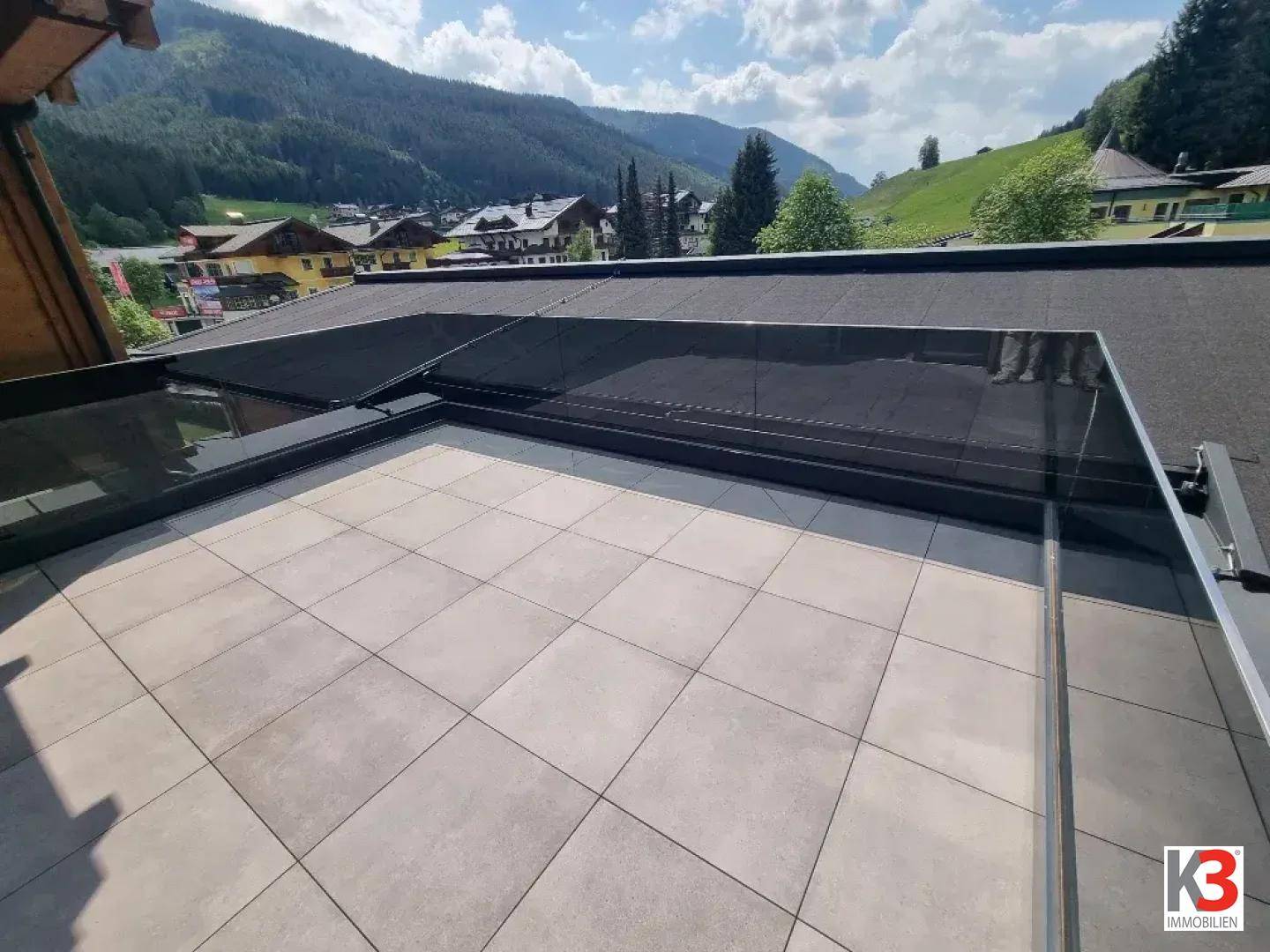 Große geflieste Terrasse mit Bergblick und umliegender grüner Landschaft.