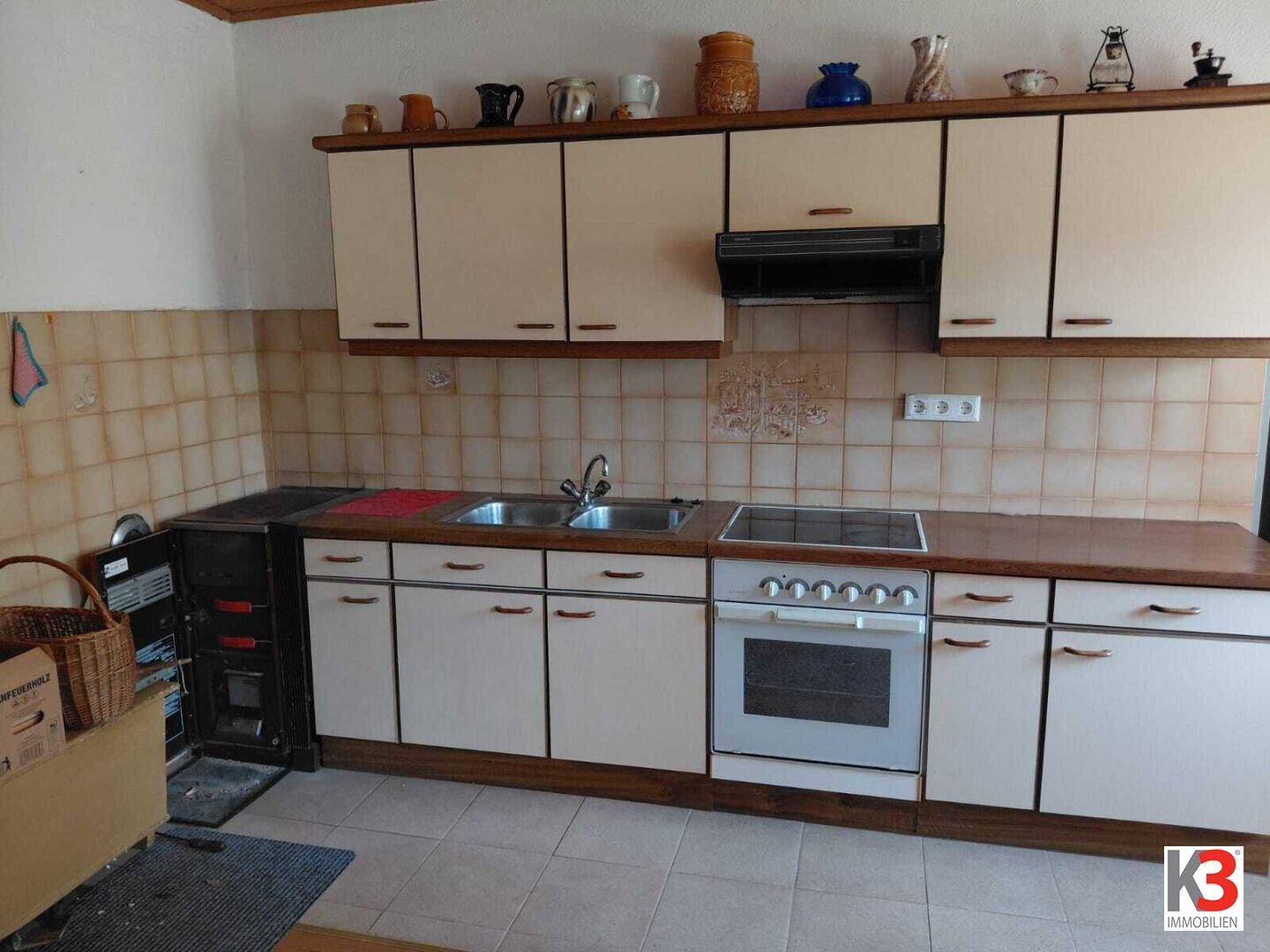 Funktionale Küche im traditionellen Stil mit beigen Schränken, Fliesen und älteren Geräten.