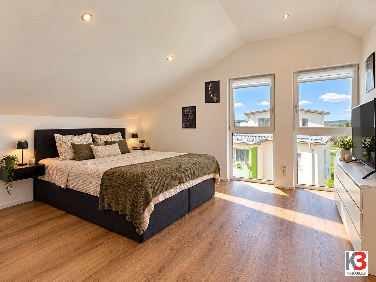 Gemütliches Schlafzimmer im Dachgeschoss mit Holzboden, großen Fenstern und viel Tageslicht.