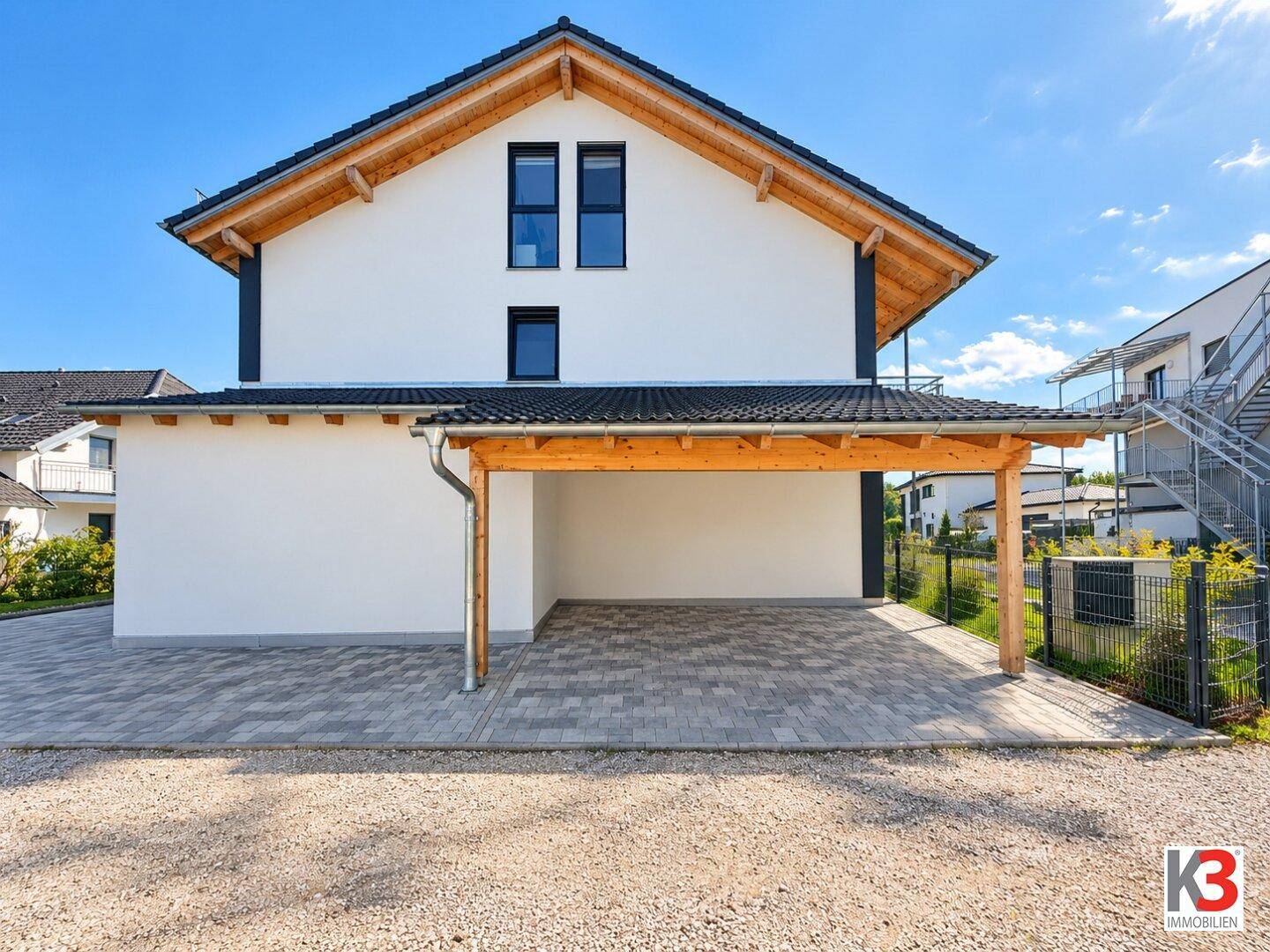 Moderne Doppelhaushälfte mit Carport, gepflasterter Einfahrt und Satteldach.