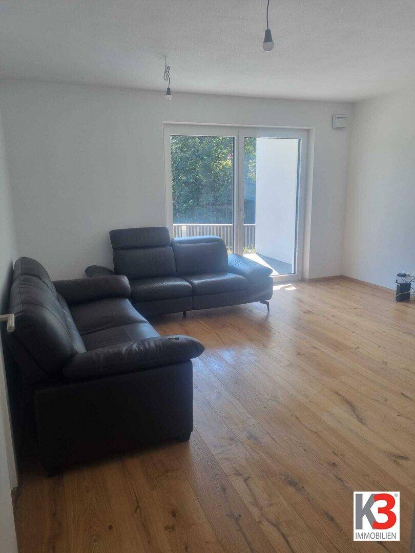 Geräumiges Wohnzimmer mit Parkettboden und viel Tageslicht durch die große Terrassentür.
