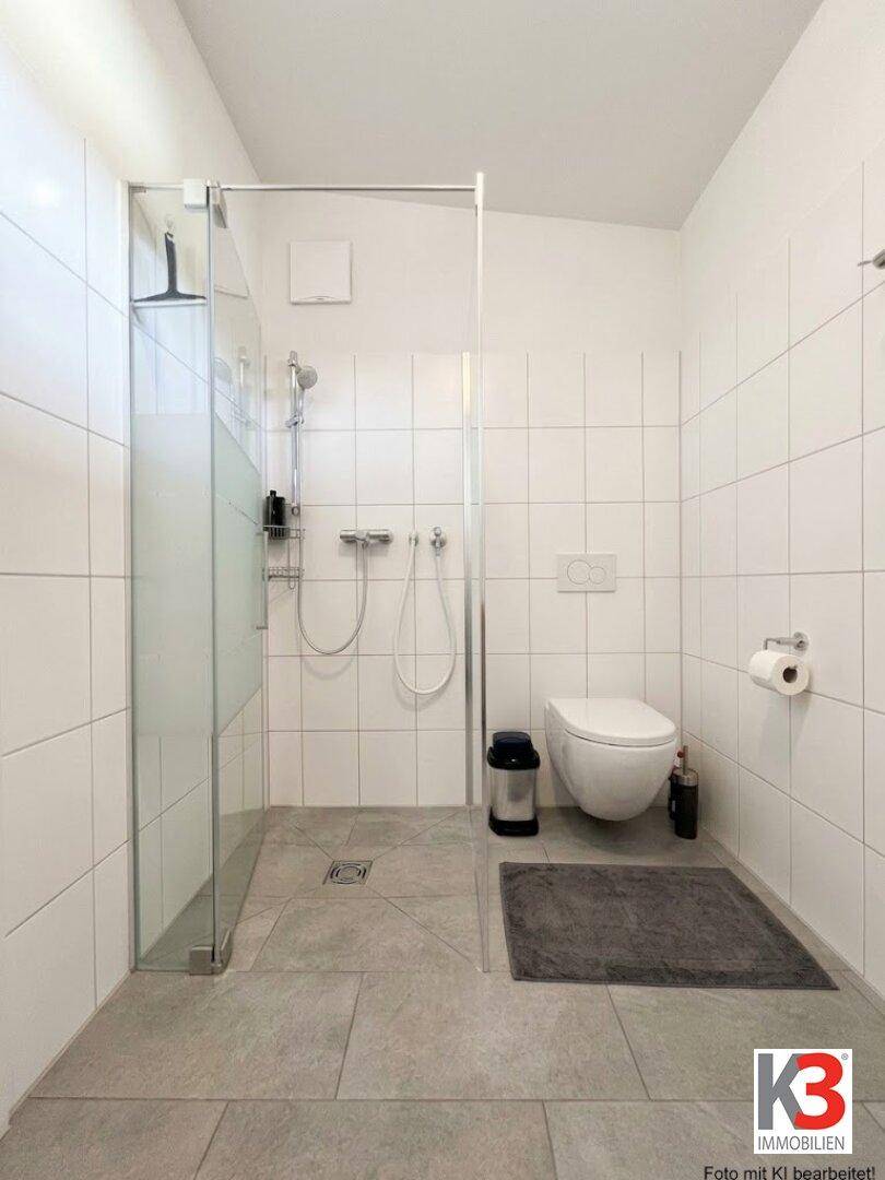 Modernes Badezimmer mit weißen Wandfliesen, ebenerdiger Dusche und wandhängendem WC.