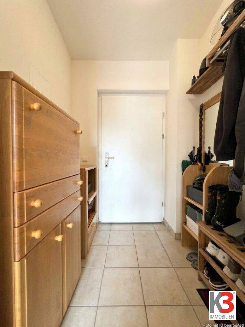 Heller Flur mit Fliesenboden und praktischen Holzmöbeln für Schuhe und Garderobe.