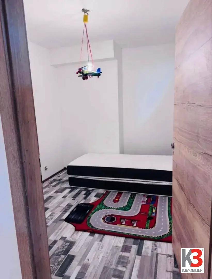 Helles Schlafzimmer mit Holzboden, einem Bett und spielerischem Flugzeug-Deckenlicht.