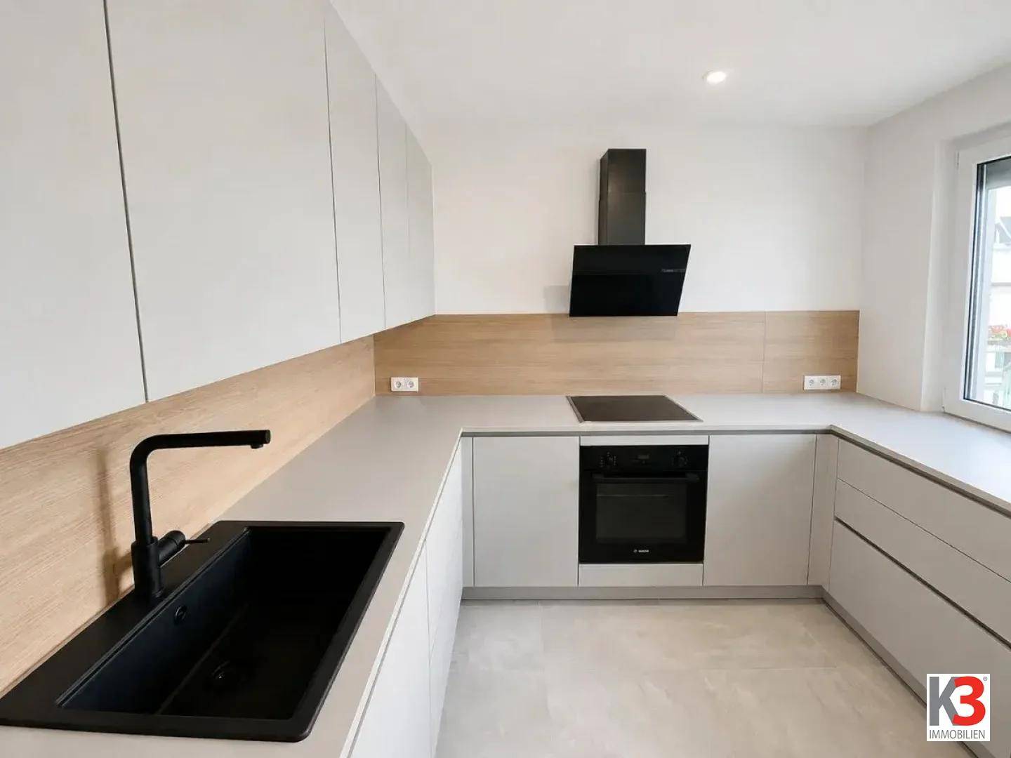 Helle, moderne Küche mit Fenster, ausgestattet mit hellgrauen Schränken und integrierten Geräten.