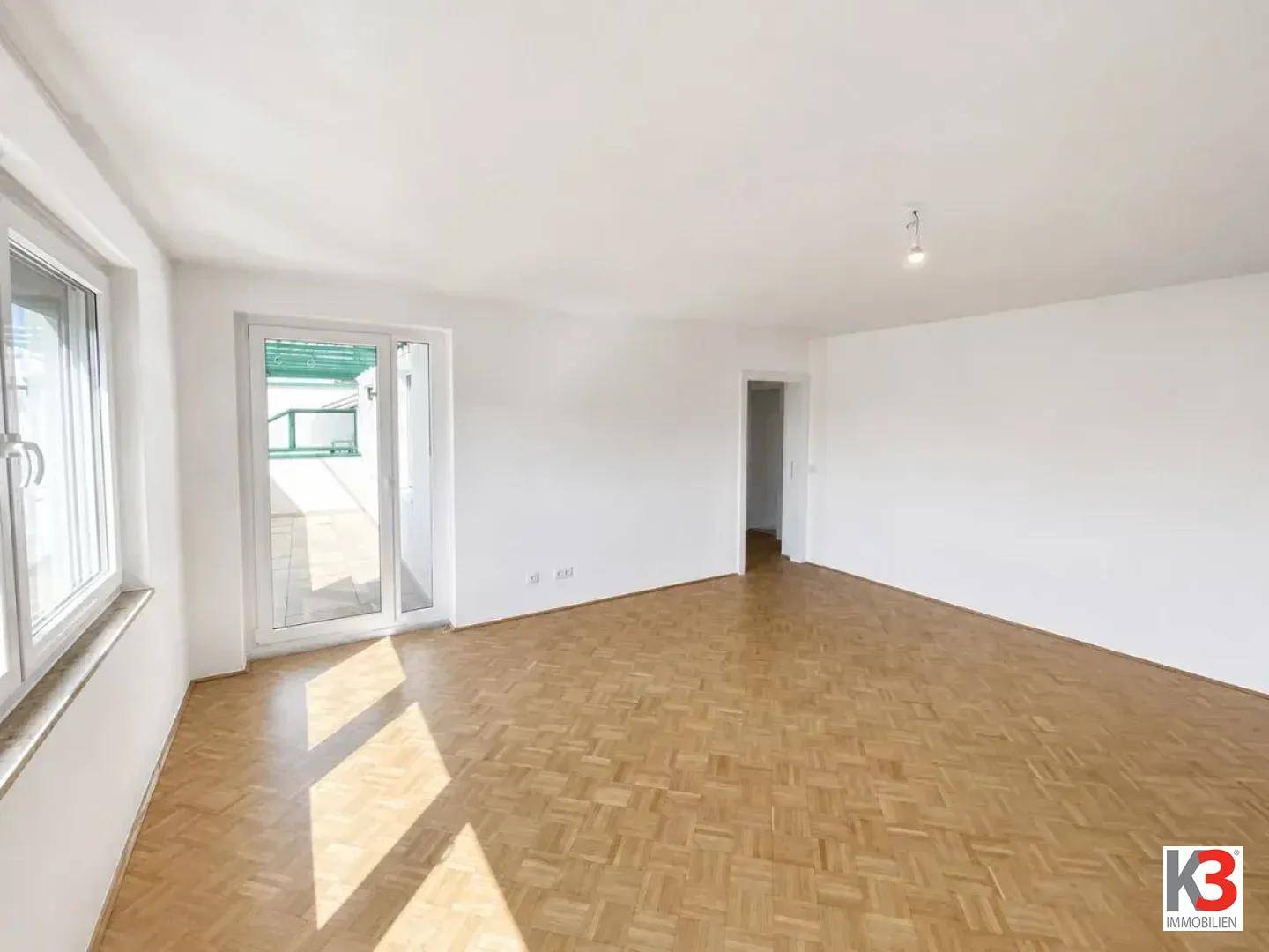 Helles Wohnzimmer mit Fischgrätparkettboden, weißen Wänden und direktem Zugang zu einem Außenbereich.