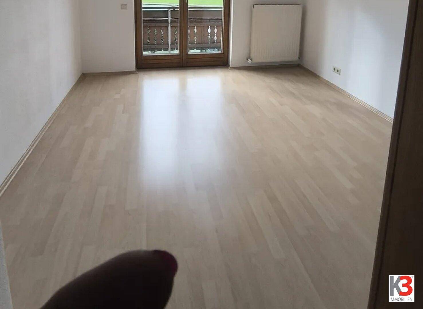 Geräumiges Schlafzimmer mit hellem Parkettboden und Balkonzugang, unmöbliert.