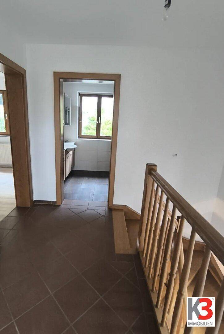 Flur mit Fliesenboden und Zugang zur Küche sowie zur Treppe.