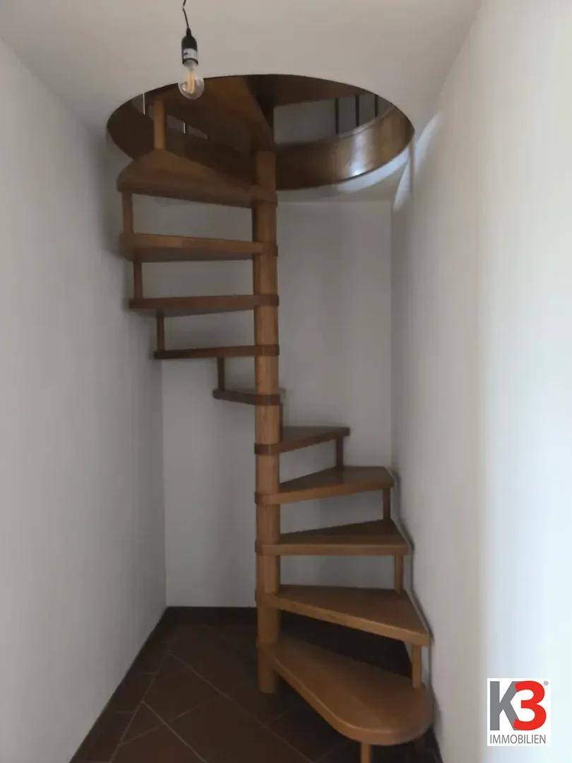 Wendeltreppe aus Holz führt in die obere Etage, in einem schmalen Treppenhaus.