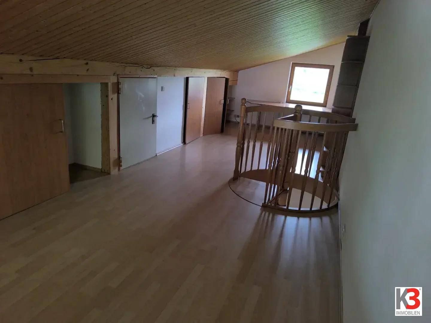 Ausgebauter Dachboden mit Holzbalkendecke, Laminatboden und Dachfenster.