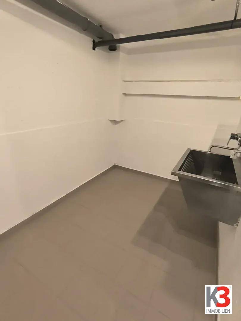 Waschküche oder Hauswirtschaftsraum mit Waschbecken und gefliestem Boden.