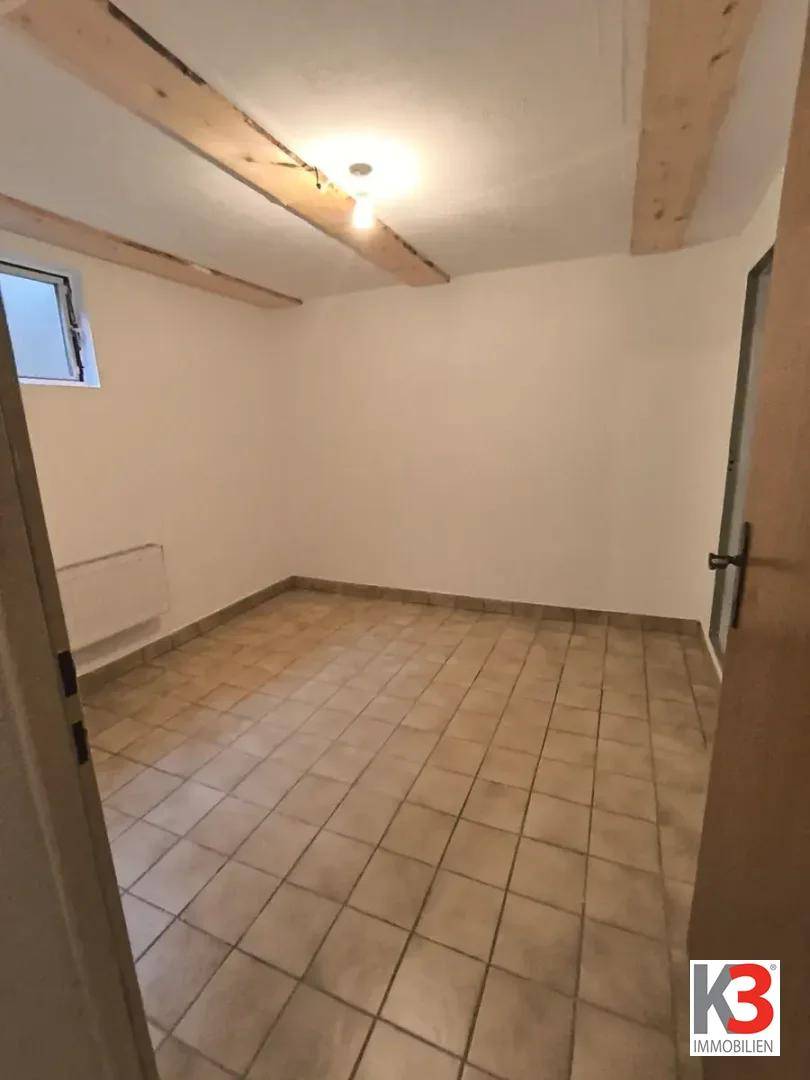 Kellerraum mit Holzbalken an der Decke und Fliesenboden, vielseitig nutzbar.