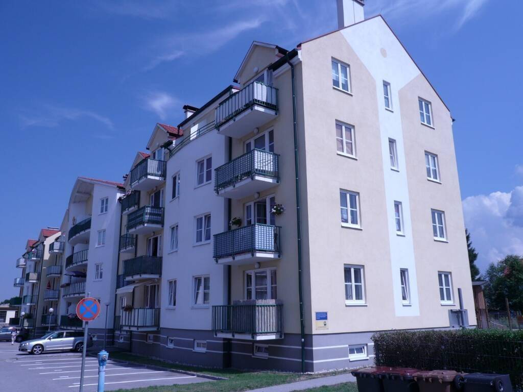 Wohngebäude mit beiger und weißer Fassade, mehreren Balkonen und gepflegter Umgebung.