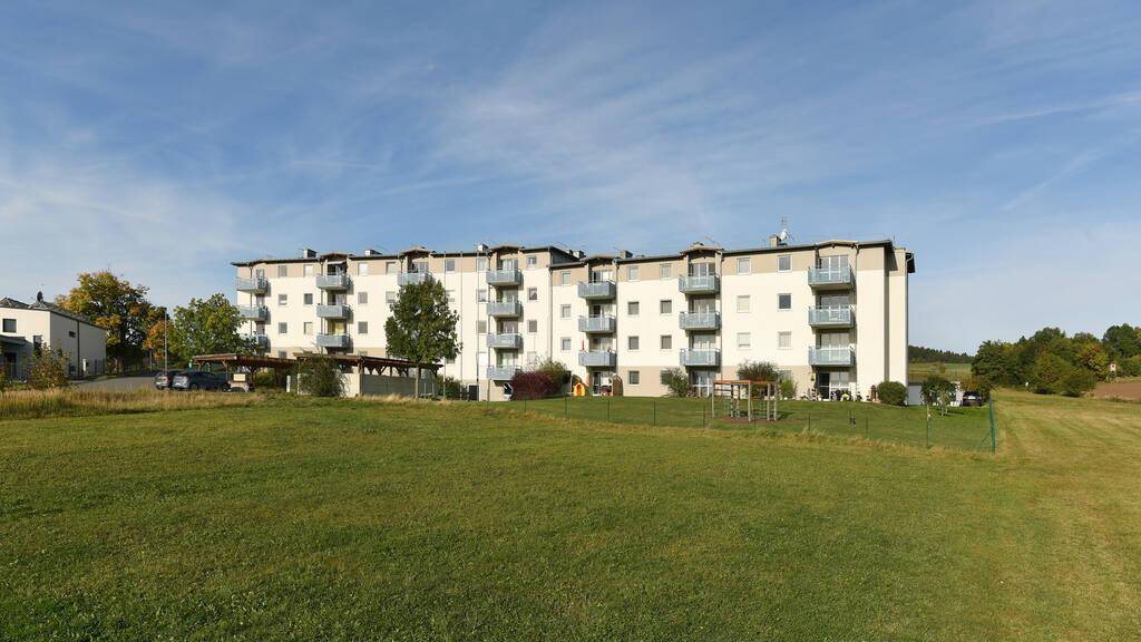 Apartmentgebäude mit zahlreichen Balkonen und weitem Blick über die umliegende Landschaft und Felder.