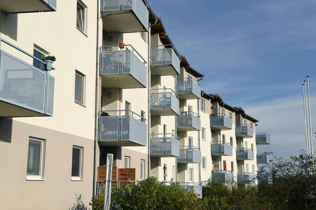 Nahaufnahme der modernen Fassade eines Apartmentgebäudes mit zahlreichen Balkonen und blauen Geländern.