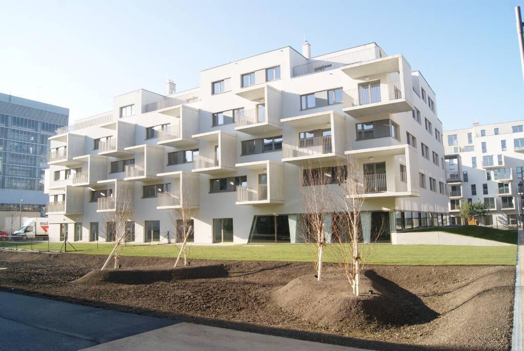 Modernes Wohngebäude mit vielen Balkonen und gepflegter Grünfläche im Vordergrund.