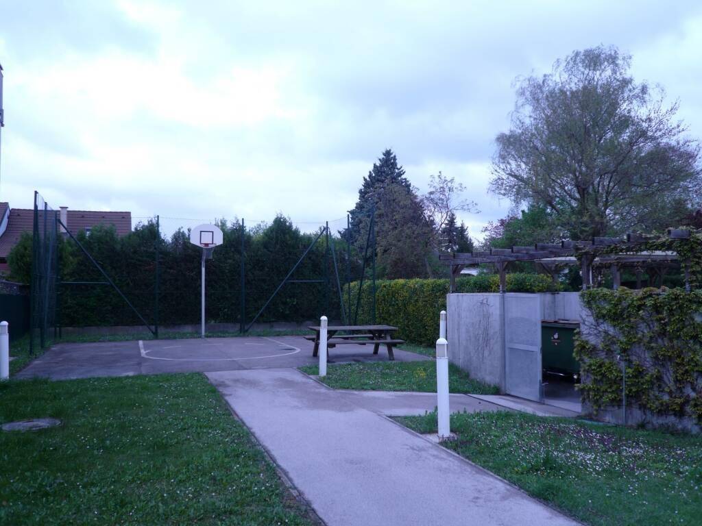 Gemeinschaftlicher Sportbereich mit Basketballplatz, Picknicktisch und umgebenden Grünflächen.