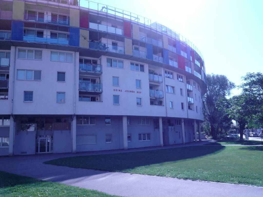 Rundes Wohngebäude mit farbigen Akzenten und einer gepflegten Grünfläche im Vordergrund.
