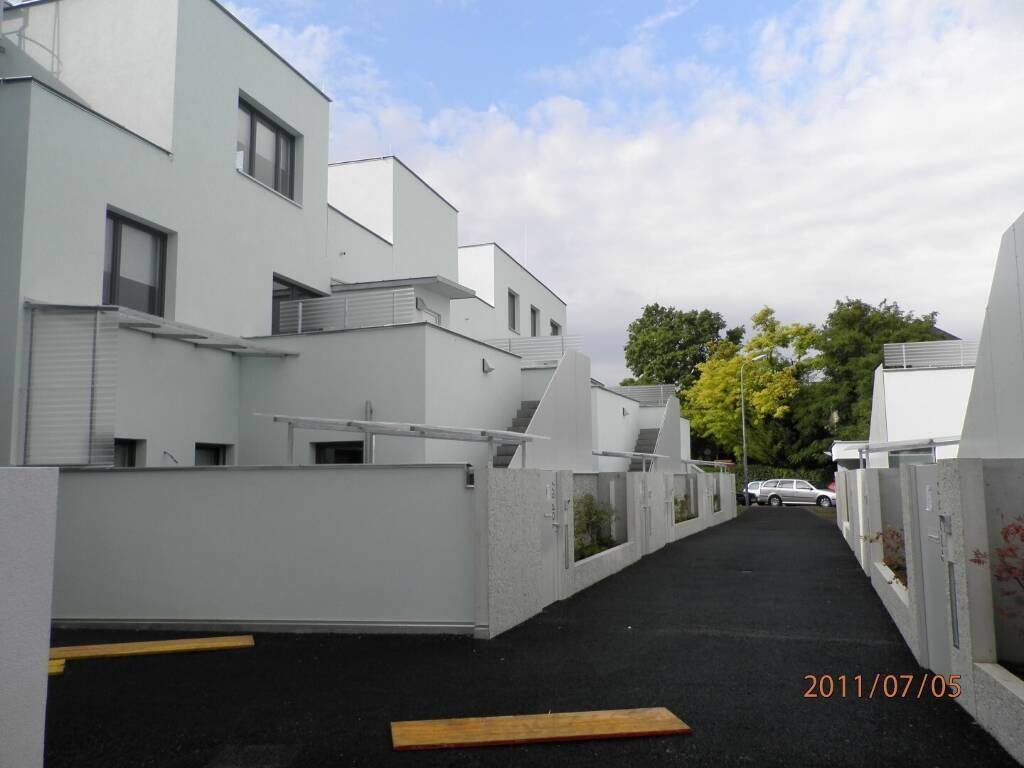 Moderne weiße Reihenhäuser mit minimalistischer Architektur und dunklem Zufahrtsweg.