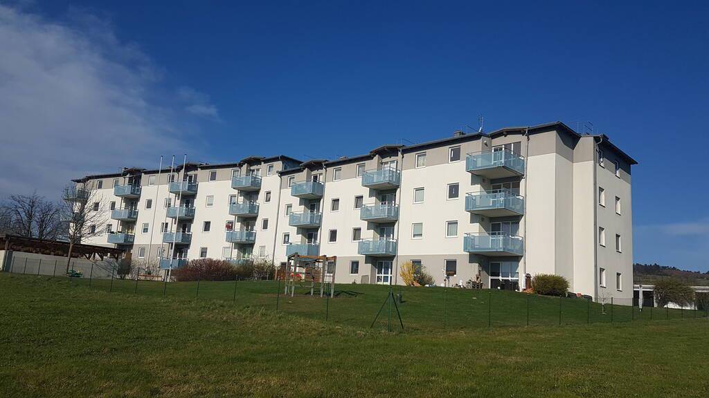 Gesamtansicht einer Wohnanlage mit Balkonen und weitem Blick über eine weitläufige grüne Landschaft.