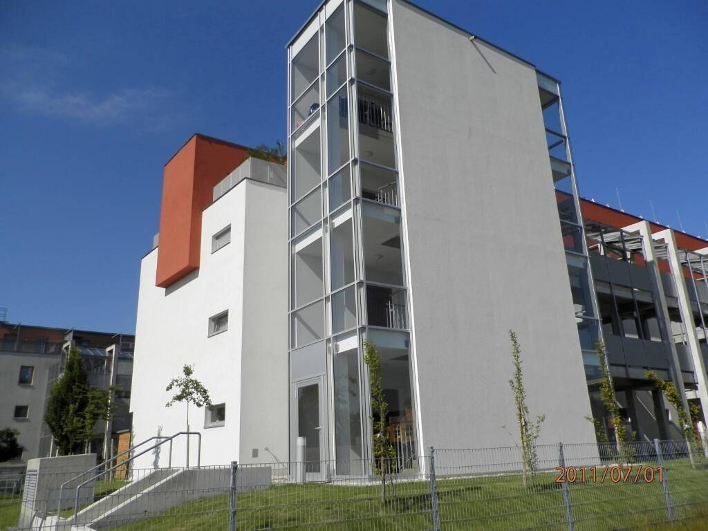 Architektonisch modernes Gebäude mit auffälliger Glasfassade und externem Aufzug.