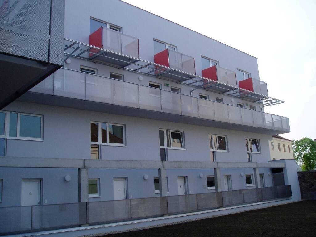 Moderne Gebäudefassade mit mehreren Balkonen und großen Fenstern.