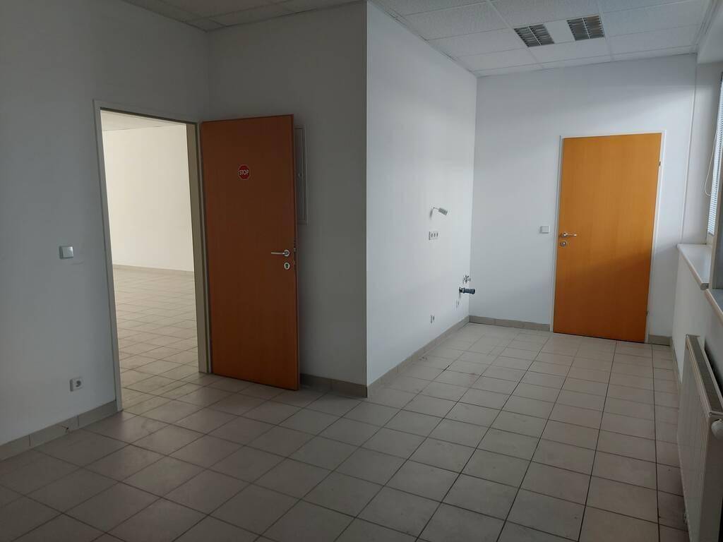 Innenraum mit Fliesenboden und zwei Holztüren, die zu weiteren Räumen führen, in einem Geschäftsbereich.