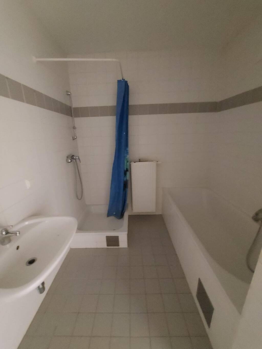 Funktionales Badezimmer mit weißen Fliesen, Waschbecken, Dusche und Badewanne.