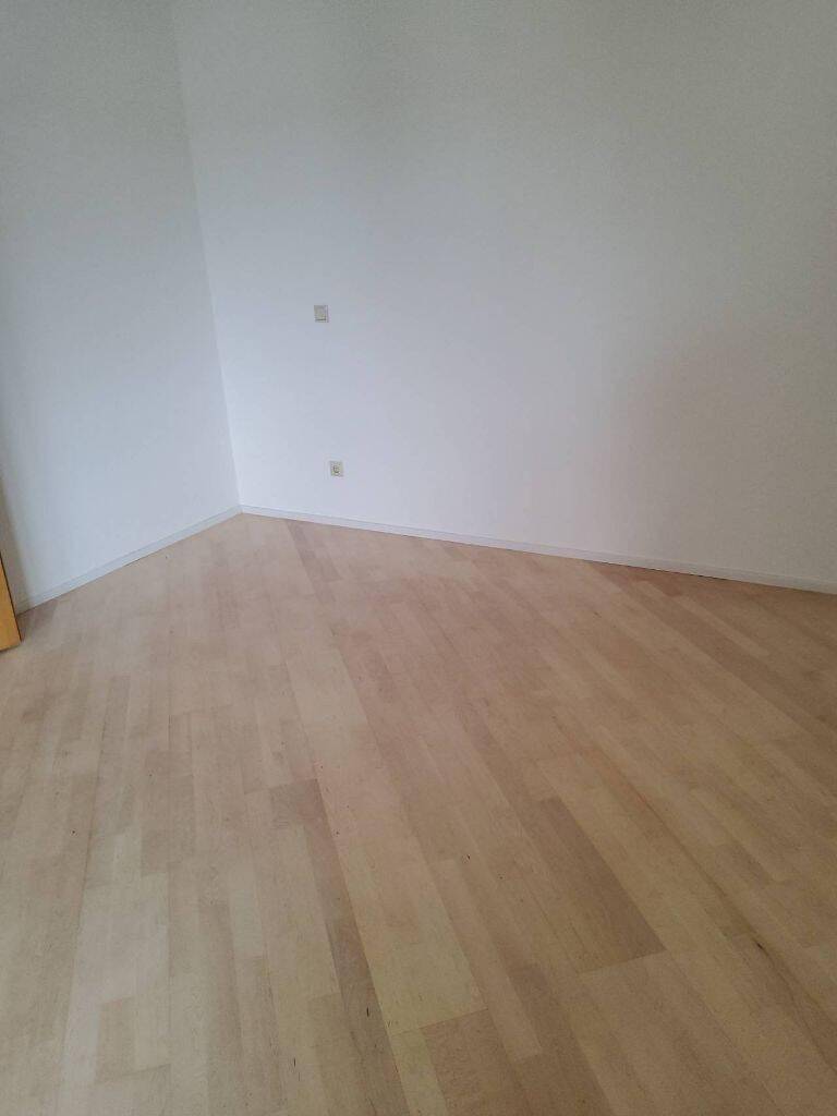 Leerer Raum mit hellem Holzboden und weißen Wänden, bereit für individuelle Einrichtung.