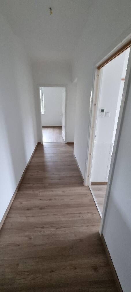 Heller Flur mit modernem Laminatboden, weißen Wänden und Türen zu angrenzenden Zimmern.