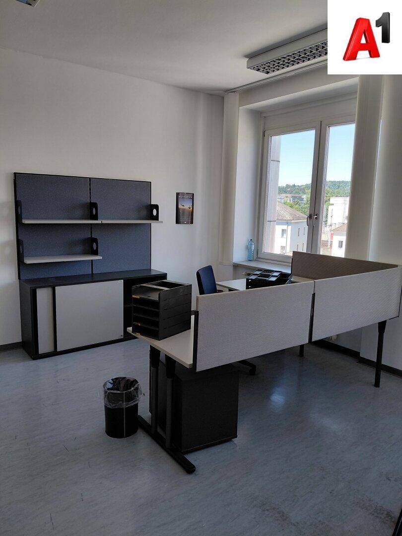 Helles Büro mit modernem Schreibtisch, Bürostuhl und Stauraummöbeln am Fenster.